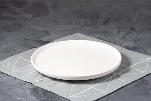 Empty white plate over gray concrete background.