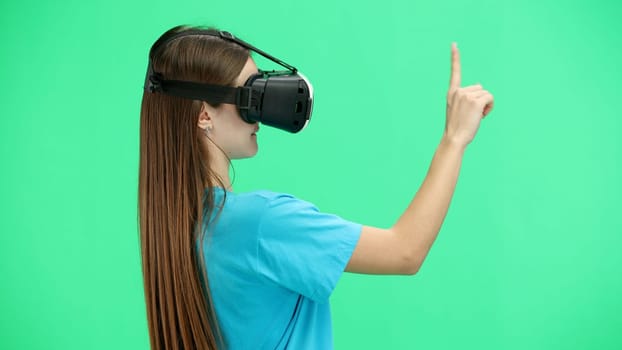 Woman, close-up, on a green background, wearing VR glasses.
