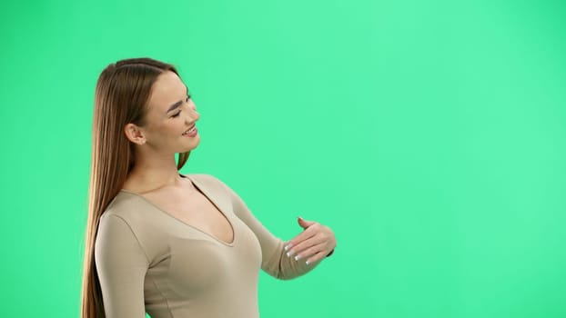 A woman, close-up, on a green background, calls to her.