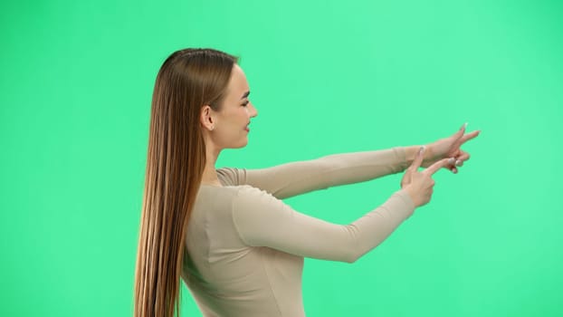 A woman, close-up, on a green background, points to the side.