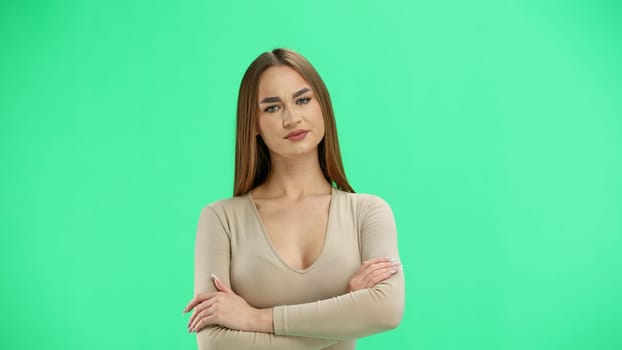 A woman, close-up, on a green background, crossed her arms.