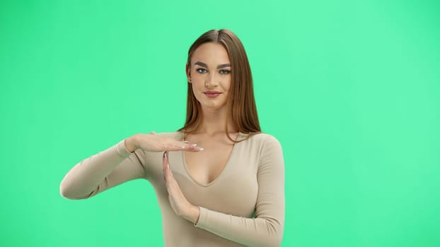 A woman, close-up, on a green background, shows a pause.