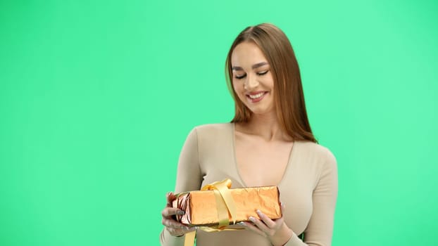 Woman, close-up, on a green background, with a gift.