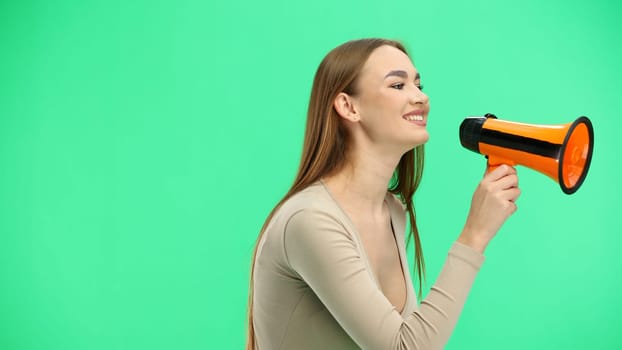 Woman, close-up, on a green background, with a megaphone.