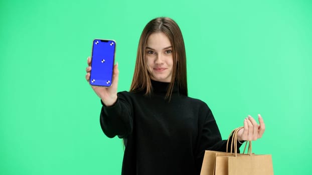 Woman, close-up, on a green background, with bags and a phone.