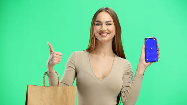 Woman, close-up, on a green background, with bags and a phone.