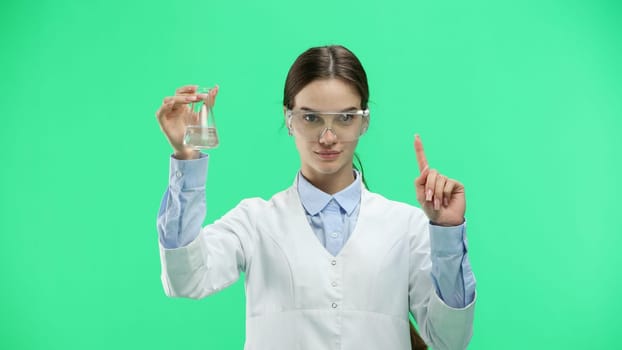 Female doctor, close-up, on a green background, holding a bottle.