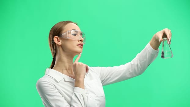 Female doctor, close-up, on a green background, holding a bottle.