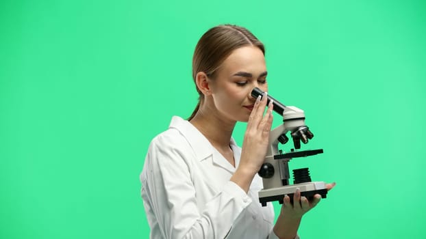 Female doctor, close-up, on a green background, with a microscope.