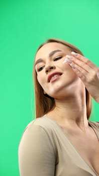 Woman's face, close-up, on a green background.