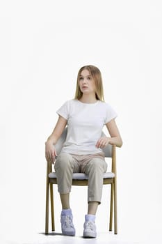 A woman, full-length, on a white background, sitting on a chair.