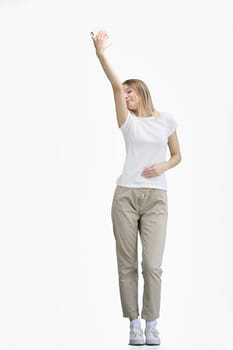 A woman, full-length, on a white background, waving her phone.