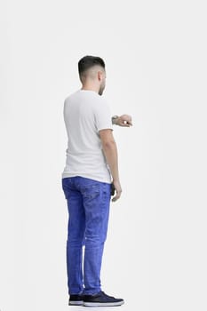 A man, full-length, on a white background, looks at his watch.