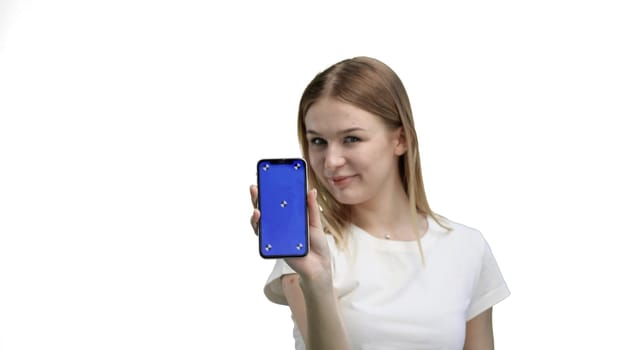 A woman, close-up, on a white background, shows a phone.