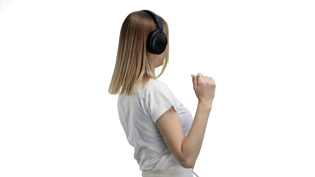 A woman, close-up, on a white background, listening to music with headphones.