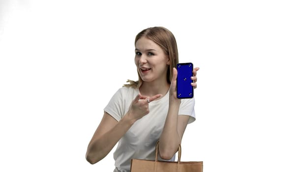 A woman, close-up, on a white background, shows a phone.