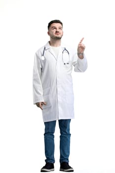 The doctor, in full height, on a white background, points up.
