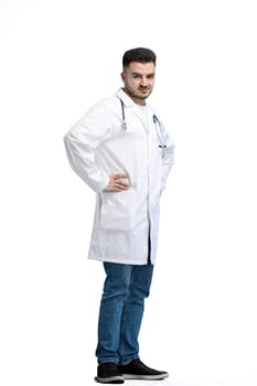 Doctor, full-length, on a white background, hands on hips.