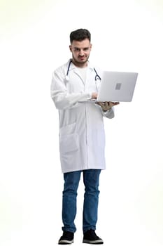 The doctor, in full height, on a white background, uses a laptop.