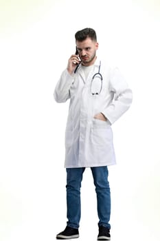 The doctor, in full height, on a white background, uses a phone.