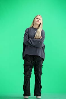 A woman, full-length, on a green background, crossed her arms.