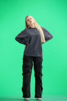 A woman, full-length, on a green background, is warming up.