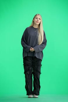 A woman, full-length, on a green background.