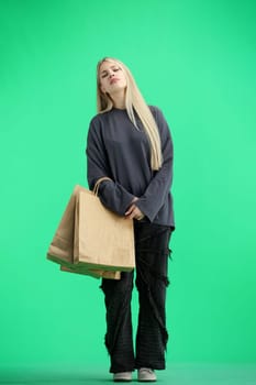 A woman, full-length, on a green background, with bags.