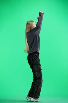 A woman, full-length, on a green background, jumps.