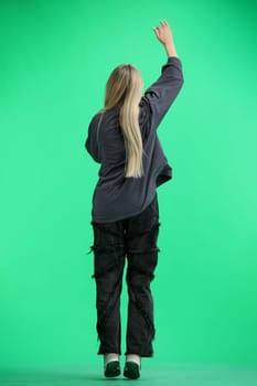 A woman, full-length, on a green background, rejoices.