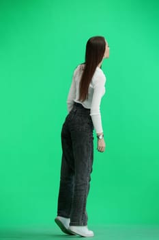 A woman, full-length, on a green background.
