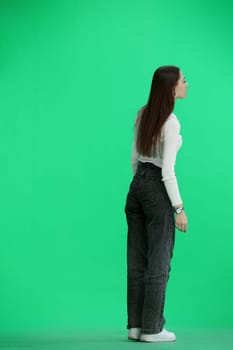 A woman, full-length, on a green background, is walking.