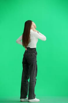 A woman, full-length, on a green background, is warming up.