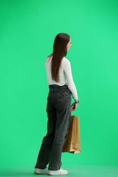 A woman, full-length, on a green background, with bags.