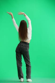 A woman, full-length, on a green background, waving her arms.
