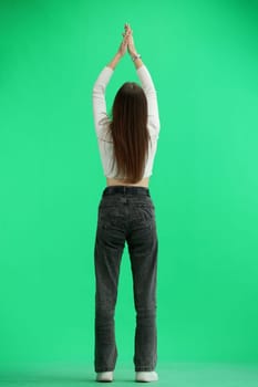 A woman, full-length, on a green background, claps.