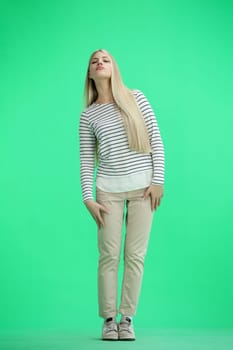 A woman, full-length, on a green background.