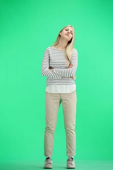 A woman, full-length, on a green background, crossed her arms.