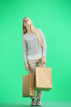 A woman, full-length, on a green background, with bags.