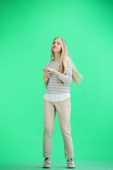 A woman, full-length, on a green background, dancing.