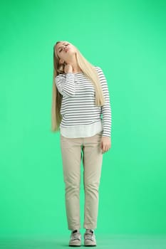 A woman, full-length, on a green background, tired.