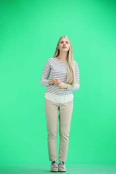 A woman, full-length, on a green background, folded her arms.