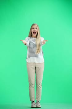 A woman, full-length, on a green background, admires.