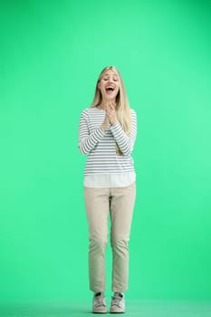 A woman, full-length, on a green background, claps.