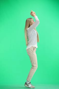 A woman, full-length, on a green background, claps.