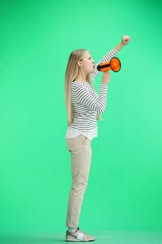 A woman, full-length, on a green background, with a megaphone.