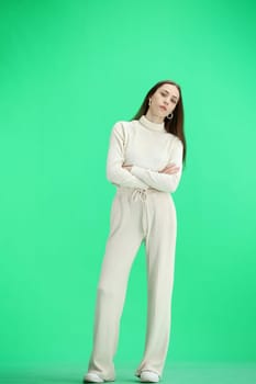 A woman, full-length, on a green background, crossed her arms.