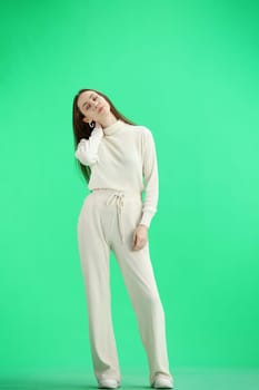 A woman, full-length, on a green background, tired.