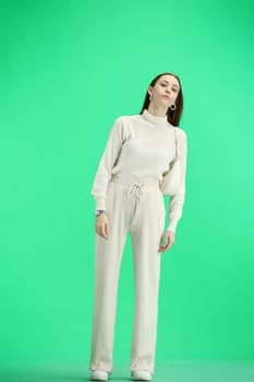 A woman, full-length, on a green background.