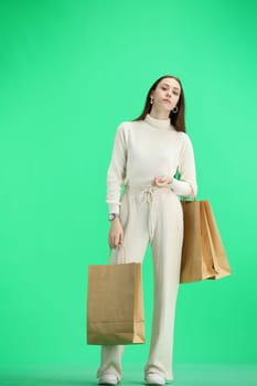 A woman, full-length, on a green background, with bags.